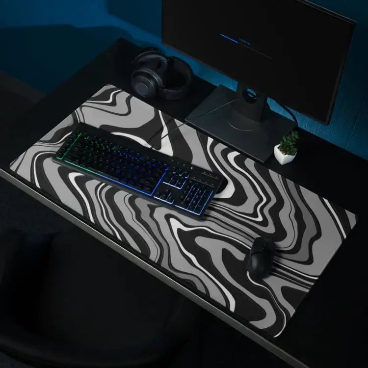 XXL gaming muismat met abstract zwart-grijs golfpatroon op een bureau met toetsenbord, muis, monitor en headset – ideaal voor een stijlvolle en functionele werk- of gameplek.